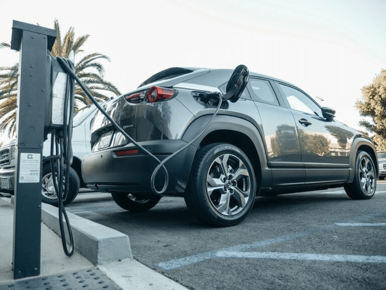 Ein Elektrofahrzeug, das an einer Ladestation aufgeladen wird, mit einem Ladekabel verbunden.