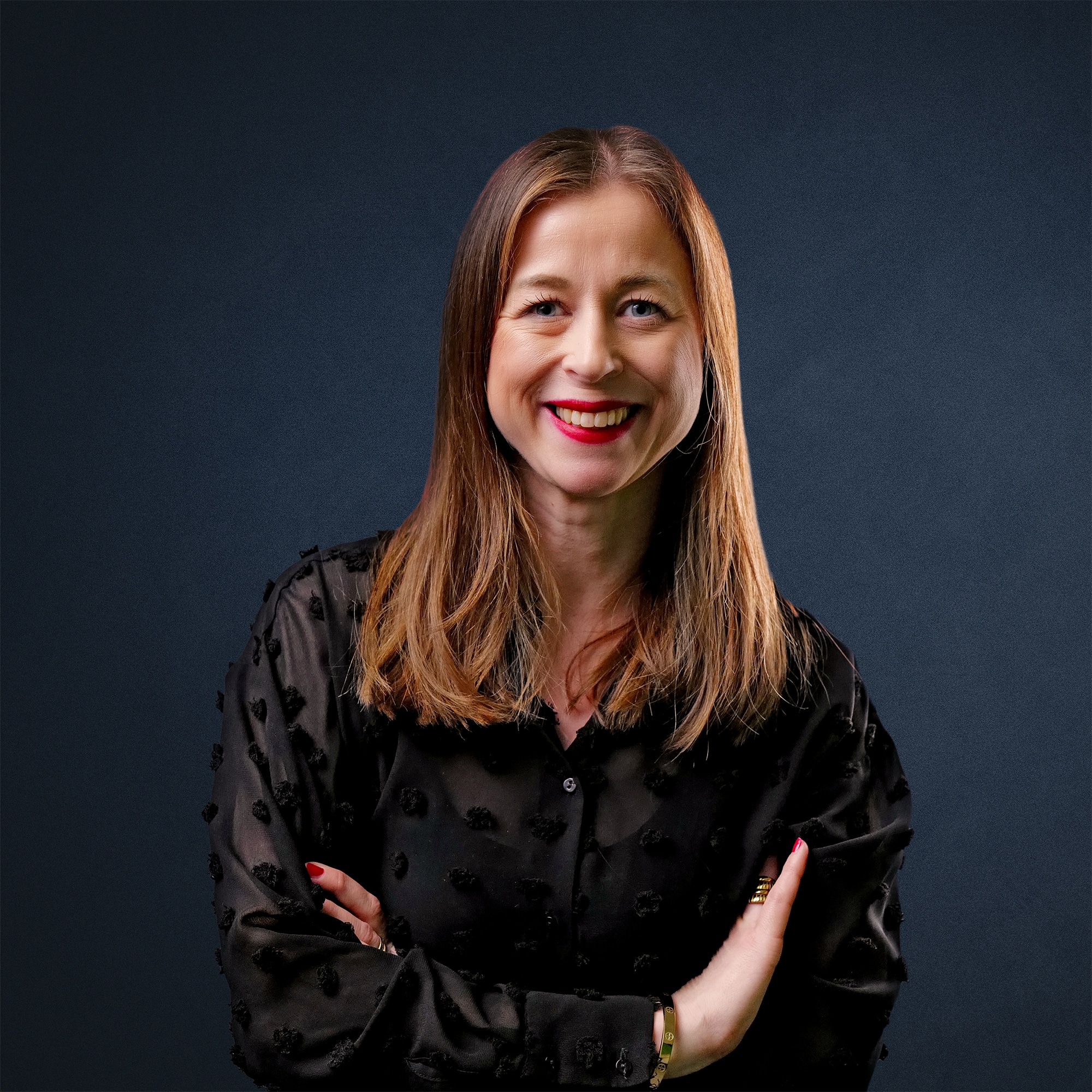 Tanja Ruhland mit langen, glatten Haaren, lächelnd in einem schwarzen Oberteil vor einem dunklen Hintergrund.