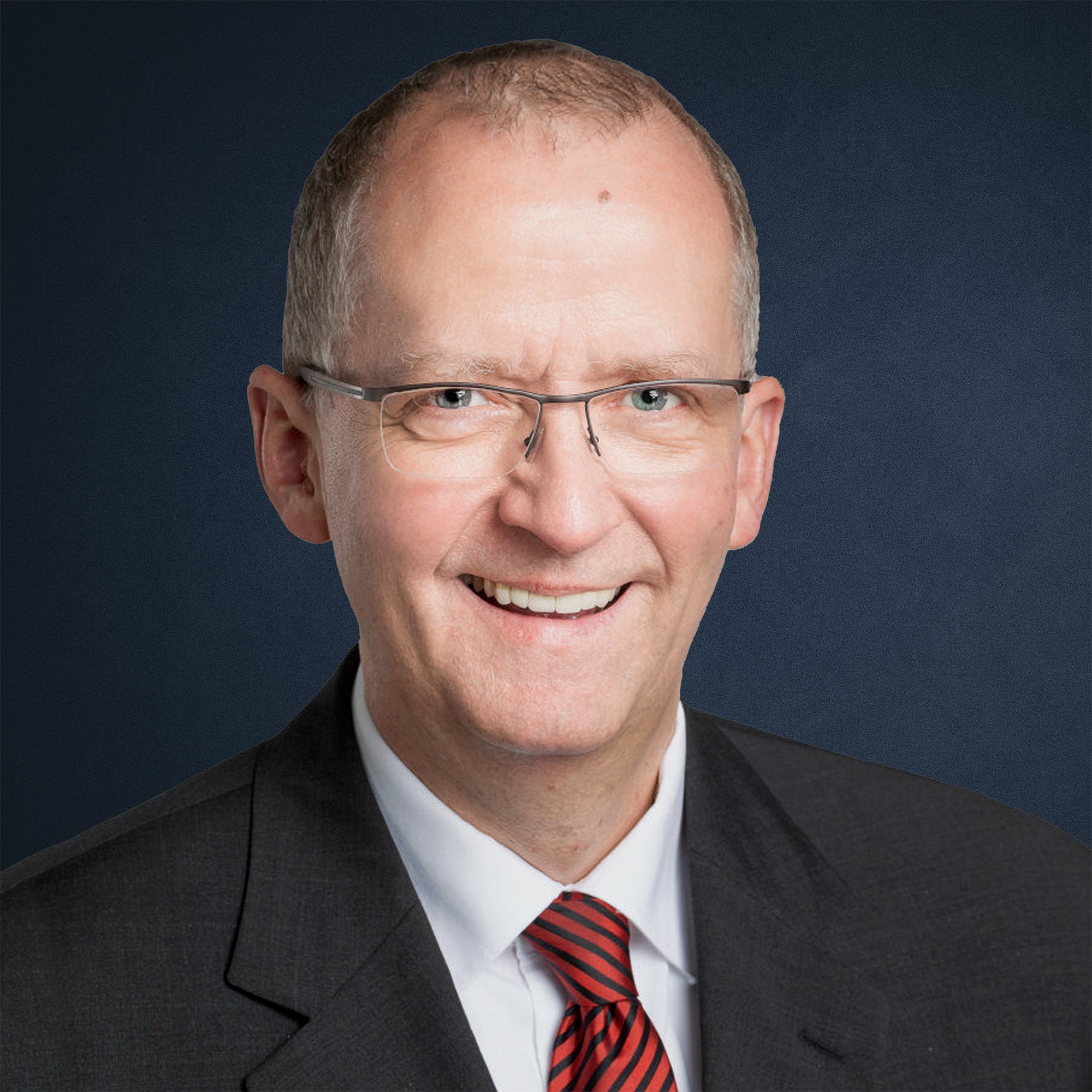 Porträt von Benedikt Laackman in einem Anzug mit Krawatte vor einem dunklen Hintergrund.
