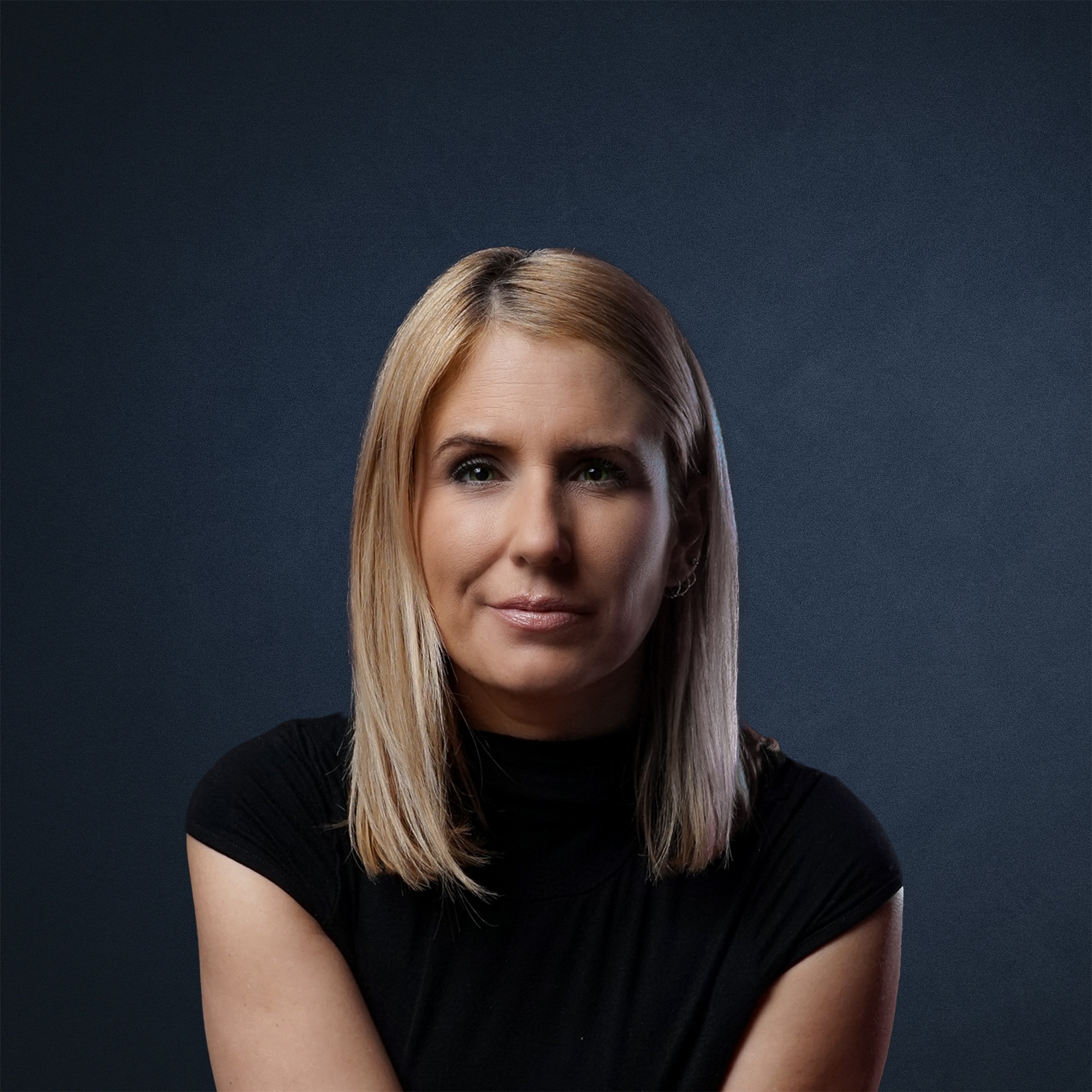 Porträt einer Frau mit blonden Haaren, die in einem schwarzen Oberteil posiert.